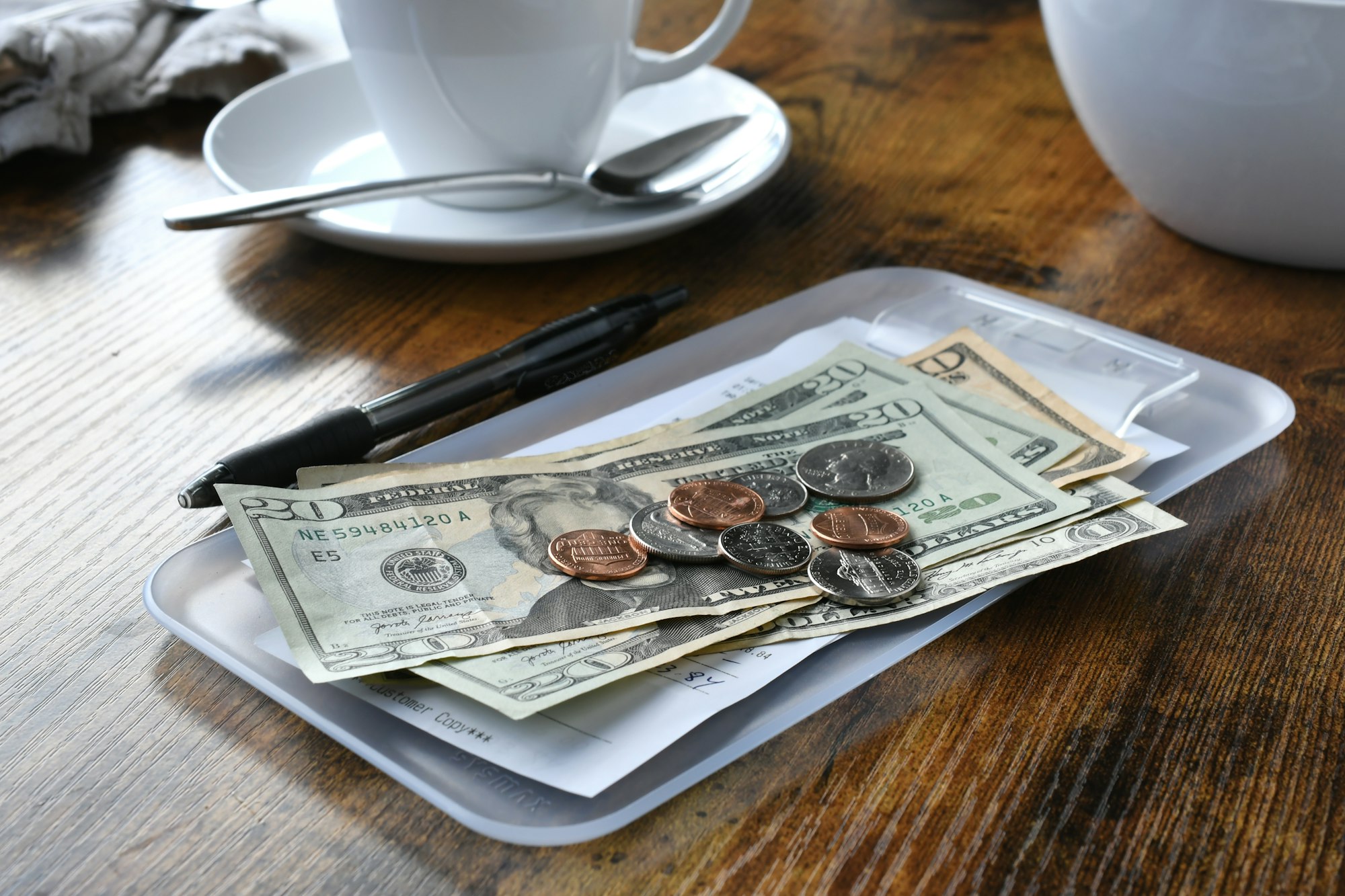 Paying for your bill tab at a restaurant cafe with cash money. Make sure you leave a tip!